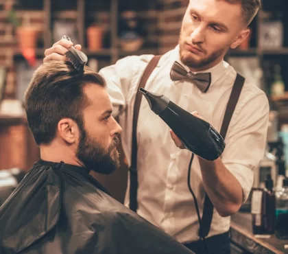 modebewusster mann beim friseur lässt sich die haare und den bart stylisch schneiden