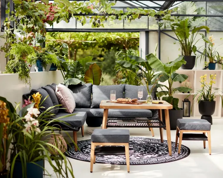 moderne und aktuelle garten deko trends 2022 mit zahlreichen pflanzen um sitzecke auf überdachter terrasse