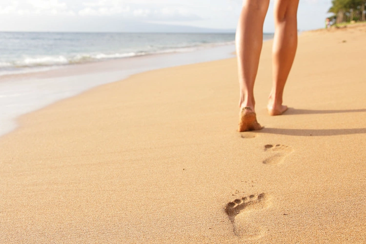 Barfuß im Sand zu laufen, ist eine gute Möglichkeit, Füße und Waden zu dehnen und zu stärken