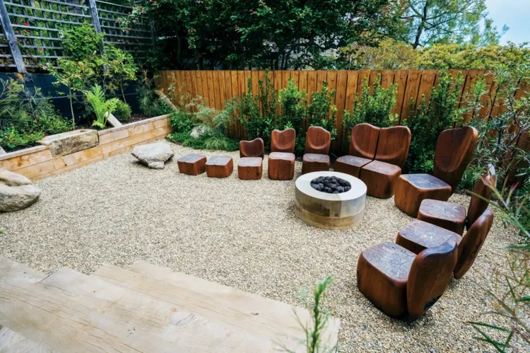 Kunstvolle Sitzecke im Garten gestalten - Skulpturale Sitzplätze aus Holz an einer Feuerstelle