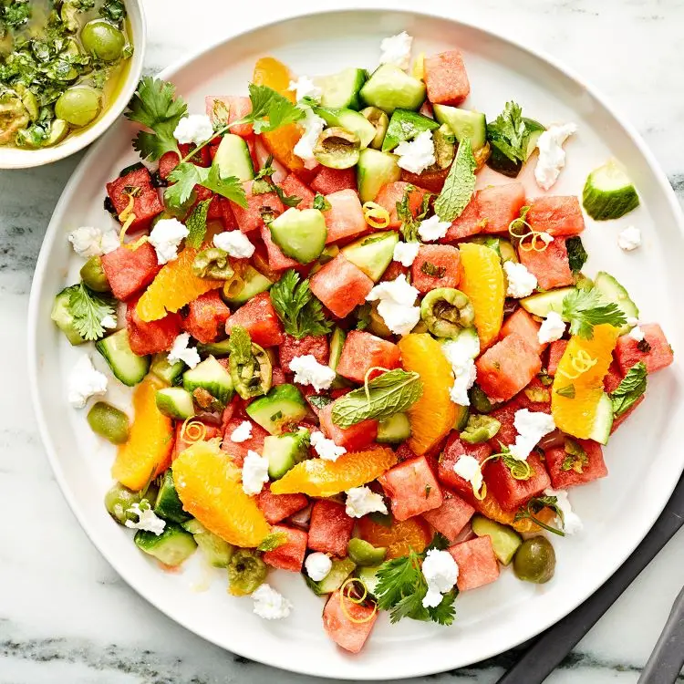 Preparing a salad with oranges and watermelon Cucumber recipe for hot days