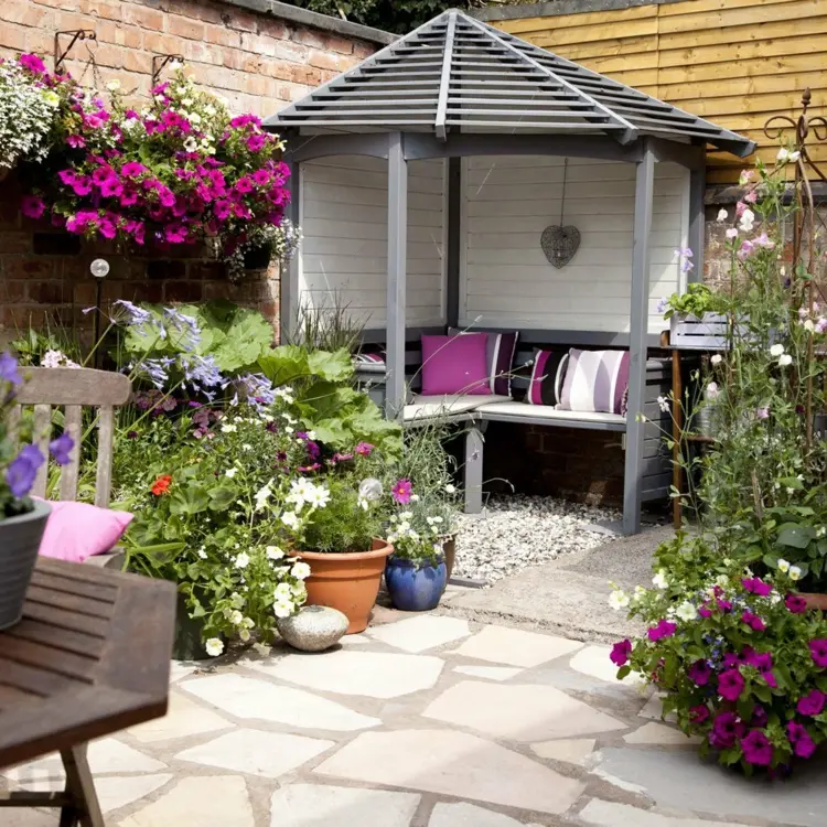 Sitzecke im Garten gestalten zwischen zwei Mauern mit Gartenlaube und Hängepflanzen