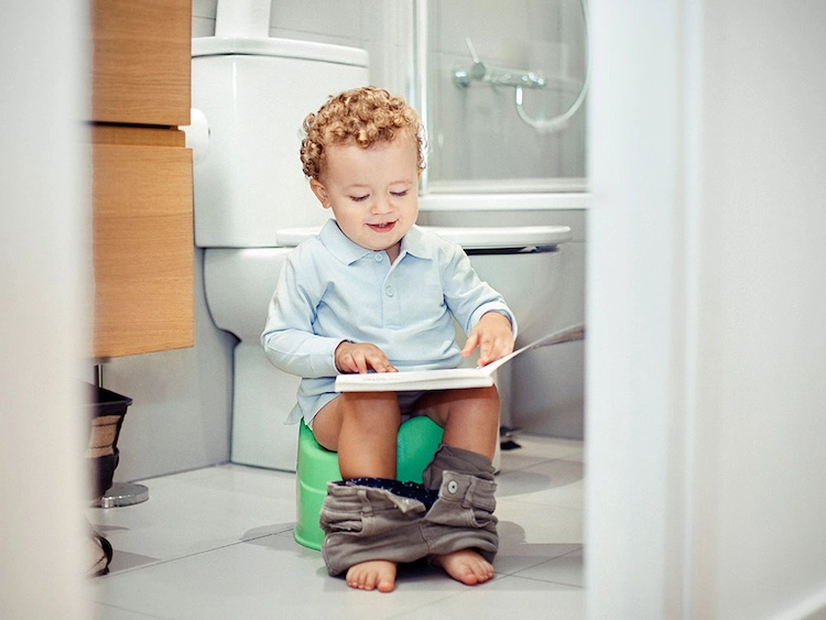 hausmittel durchfall kleinkind sitzt auf die toilette und liest ein buch