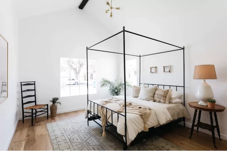 schwarzes himmelbett mit dünnem rahmen konstrastiert zu weissen wänden in einem modernen schlaftaum