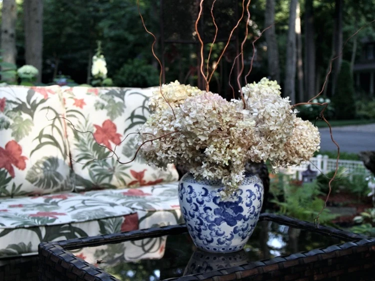 Schöne Vase mit getrockneten Hortensienblüten auf dem Terrassentisch