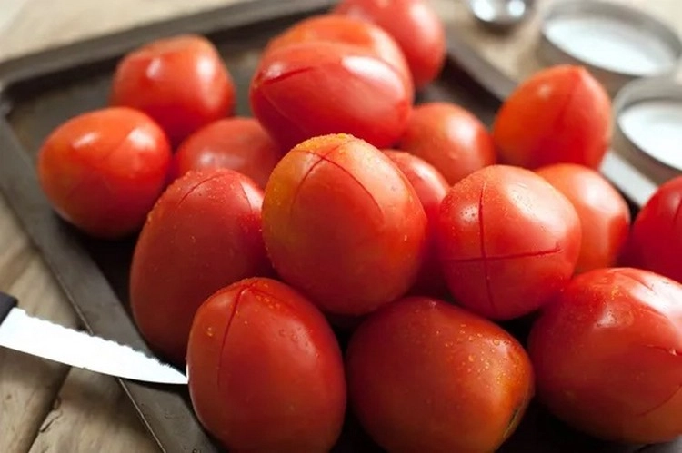 Schneiden Sie vor dem Einmachen mit einem Messer ein kleines X in den Boden jeder Tomate.