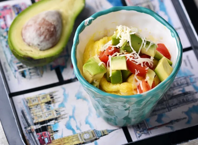 frühstück mit avocado und rührei auf gemüse mit geriebenem schafskäse für einen gesunden start des tages