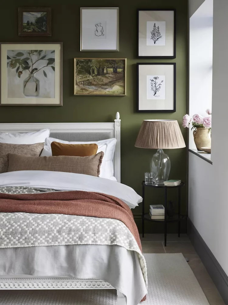 schlafzimmer in rustikalem stil mit grüner wand und mehreren bildern über weißem schlafbett