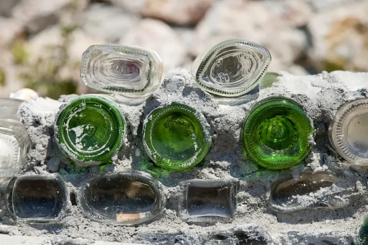 weinflaschen oder glasflaschen wiederverwenden und mit mörtel in eine gartenmauer oder zaun einbauen