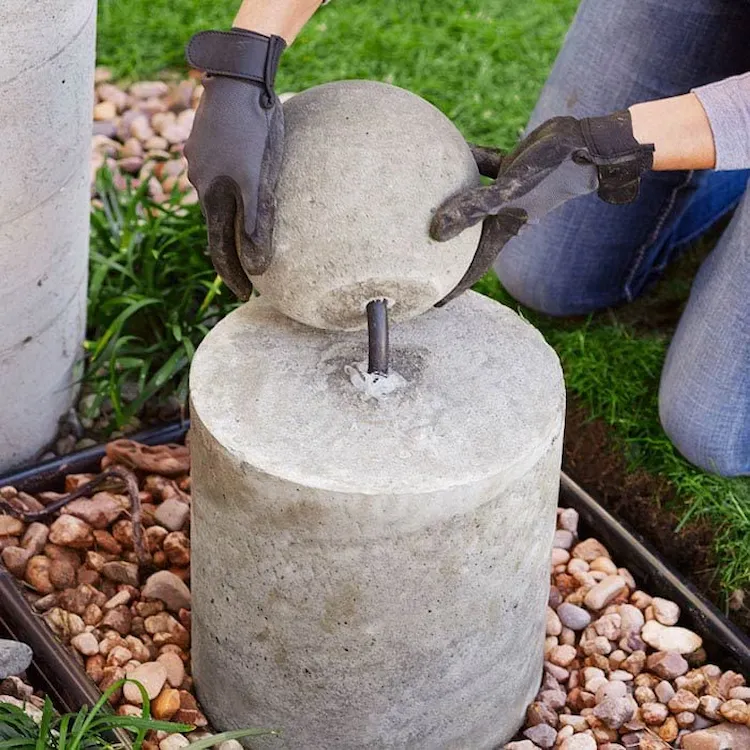 zusammenbau von betonbrunnen mit kugel und basis auf kies in einer wanne aufstellen