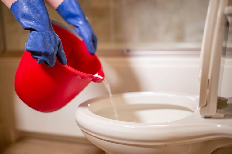eimer mit heißem wasser bei angezogenen gummihandschuhen in toilette verstopft hausmittel anwenden