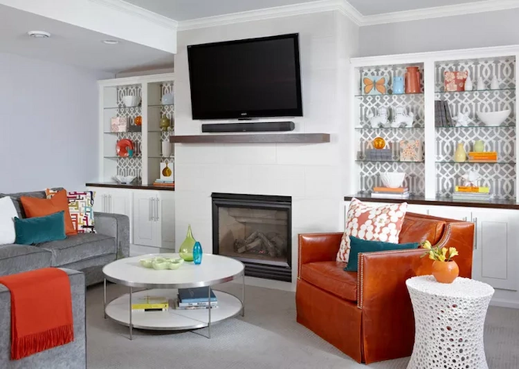farbenfroh aufgestellte accessoires und weiße einbaumöbel mit kamin in einem wohnraum