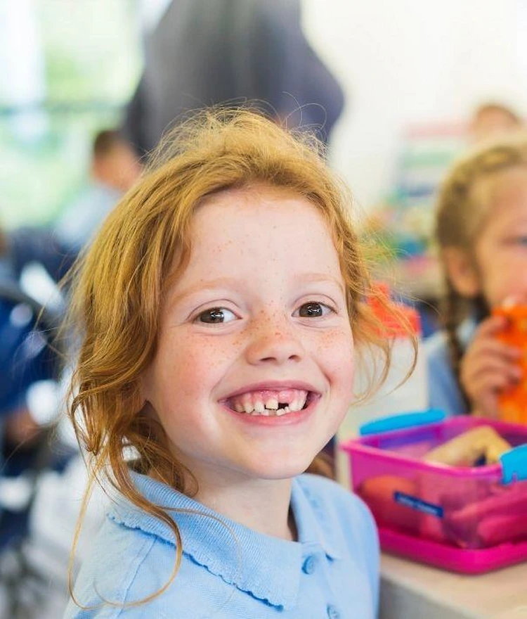lächelndes mädchen in der schule während der mittagspause kann durch ernährung die gesundheit fördern