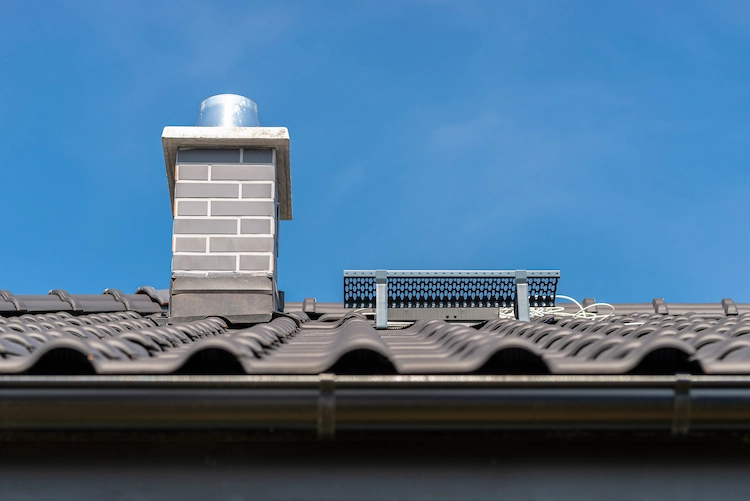 moderne installation von schornstein und solarpaneelen auf einem dach senkt heizkosten im winter