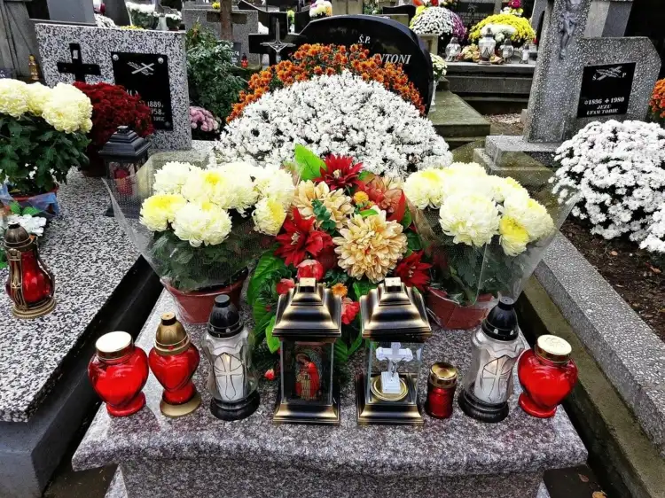 Grabgestaltung für Allerheiligen mit Blumen und Grabschmuck wie Laternen und Kerzen