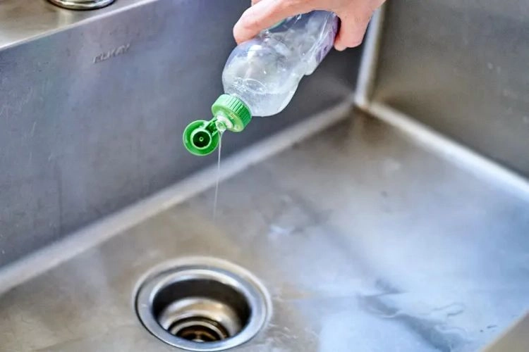 Küche reinigen - Spritzen Sie etwas Spülmittel in den Abfluss