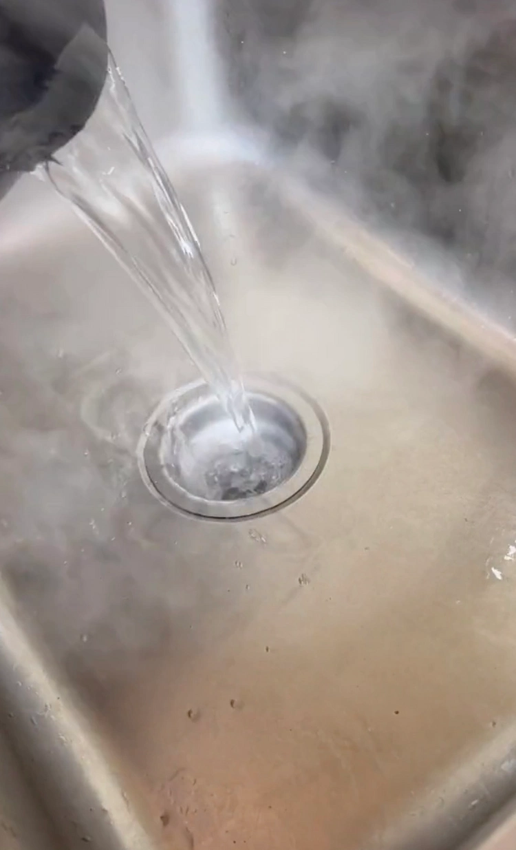 Die Abflussfliegen mit kochendem Wasser in der Spüle vertreiben