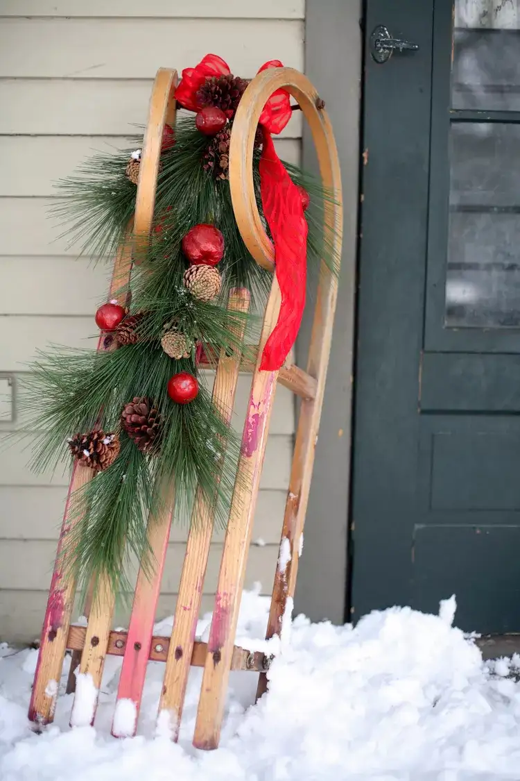 Schlitten weihnachtlich dekorieren mit Girlande mit Tannenzweigen und Christbaumkugeln
