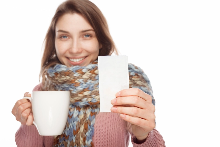 junge frau trinkt warmen tee bei einer erkältung zur linderung der symptome