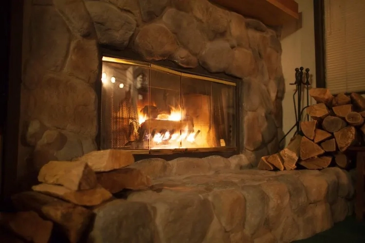 mit naturstein verkleideter kamin im winter mit einer ladung aus brennholz trocknen im wohnraum möglich