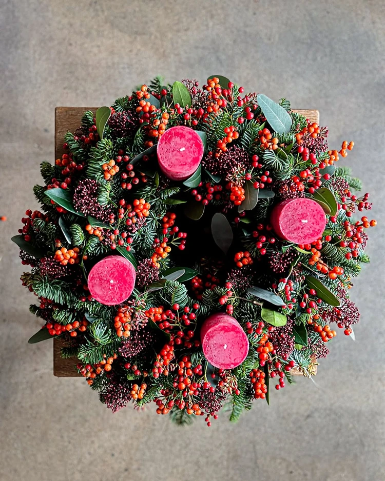 moderner adventskranz mit beeren und frischem grün