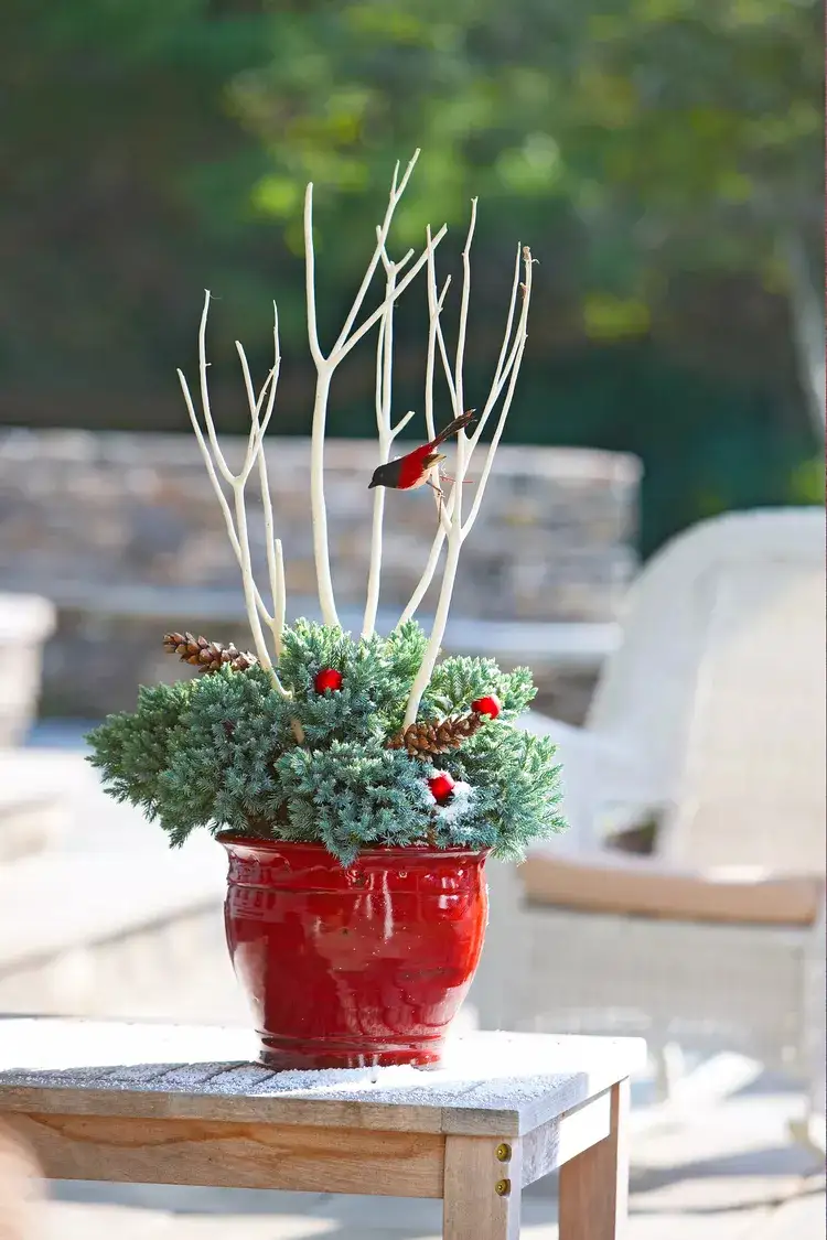 roten Kübel im Garten mit Vogelfiguren und Zweigen dekorieren