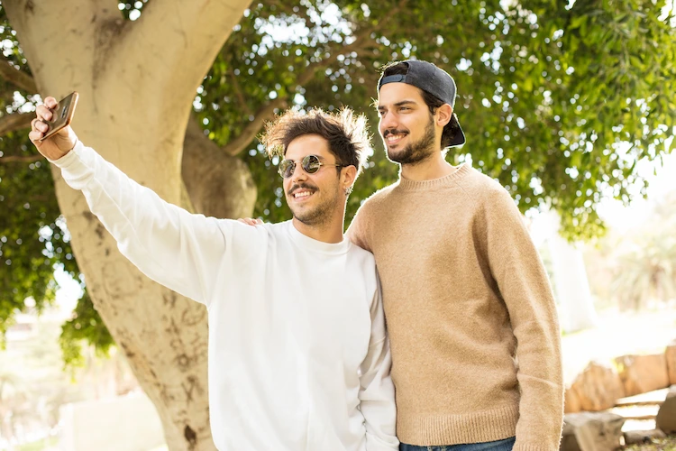 zwei junge männer mit modernen pullovern machen selfie im freien