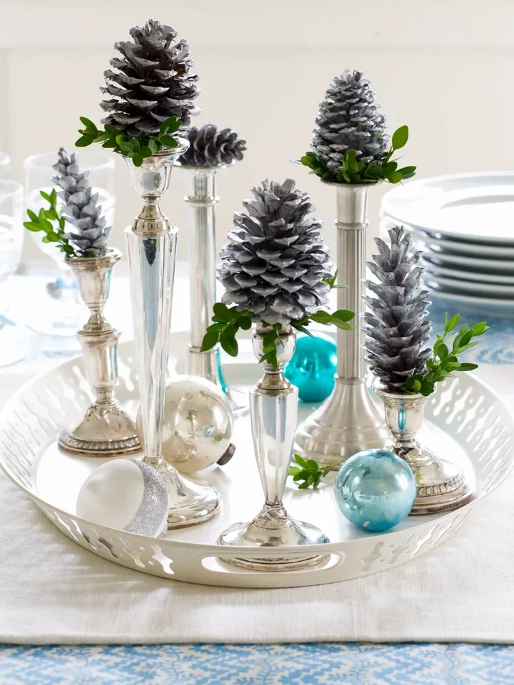 Anstelle der üblichen silbernen Kerzenständer können Sie auch einen bemalten Tannenzapfen auf den Tisch stellen