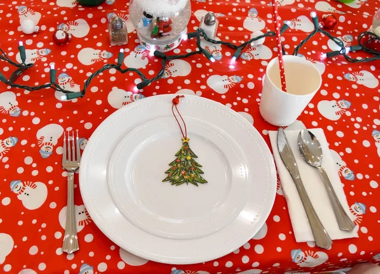 Kindertisch zu Weihnachten dekorieren - Die niedliche Schneemann-Tischdecke auf den Tisch legen