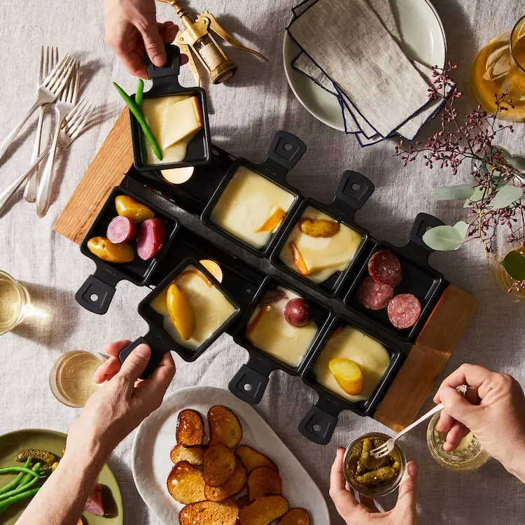 Raclette Tisch decken - Einzelne Käseportionen werden in kleine Pfännchen, sogenannte Coupelles, gelegt