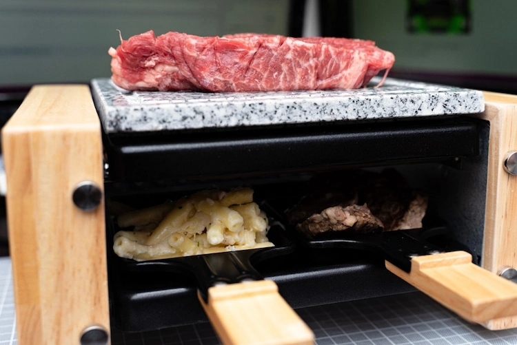 an der oberseite von raclette stein als platte für steaks und darunter andere lebensmittel zubereiten