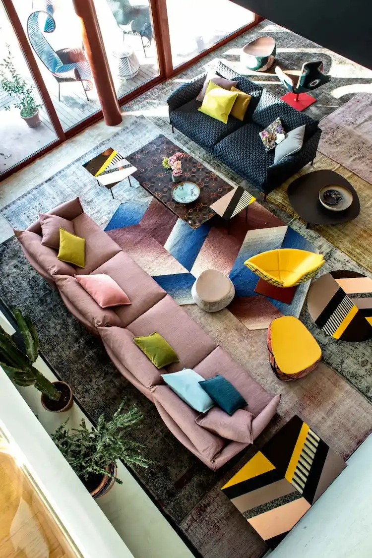 farbenfrohe innenraumgestaltung mit langem sofa und buntem teppich unter modernen designer tischen