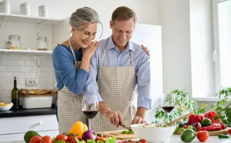 glueckliche-und-jung-aussehende-senioren-beim-kochen-mit-gesunden-lebensmitteln-fuer-ausgewogene-ernaehrung-ab-60