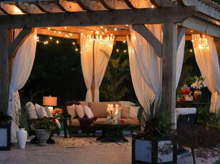 Romantischer Sitzbereich unter Überdachung mit Lichterketten, Kerzen und Pflanzen