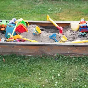 auf dem rasen aufgelegter sandkasten für kinder selber machen und mit spielzeug ausstatten