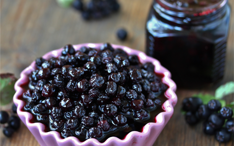aronia marmelade in einer kleinen schüssel vor einem aronia glas