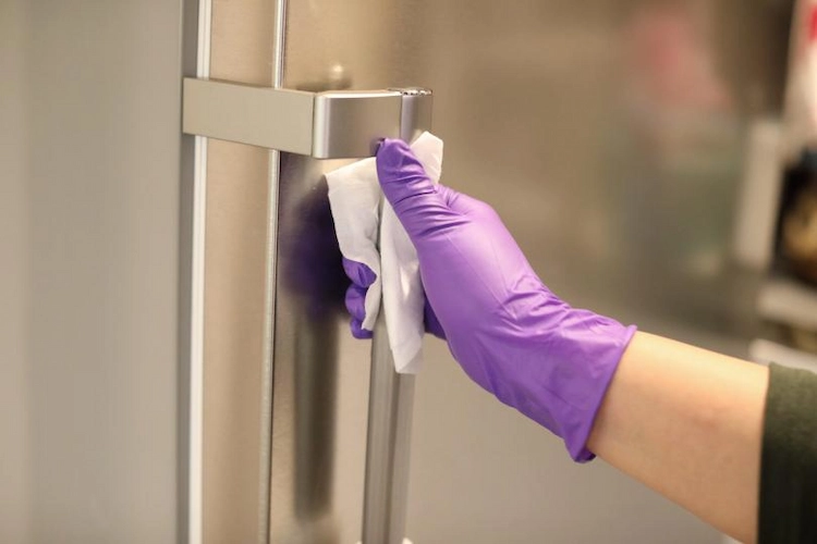 die griffe von küchengeräten wie kühlschränken oder kleingeräten mit desinfektionstüchern sauber machen