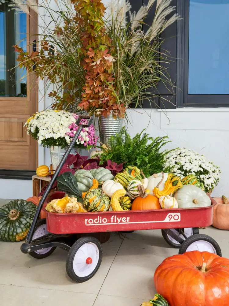 Einfache Herbstdeko für draußen mit Böllerwagen, gefüllt mit Kürbissen und Strauß aus Laub und Gräsern