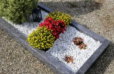 Gräber mit Steinen dekorieren - Kies, Umrandung und Blumen kombinieren