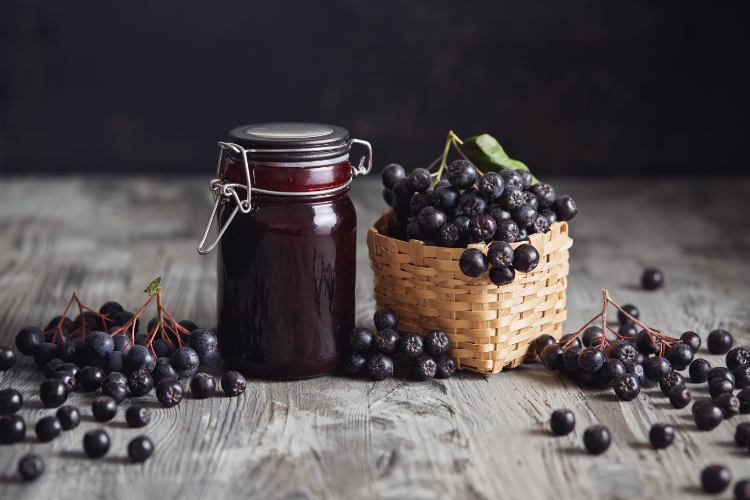 hausgemachte aronia marmelade in glaskeramik mit frischen aronia beeren