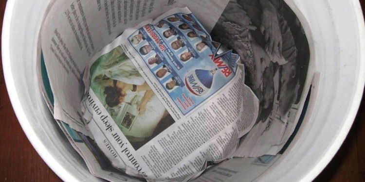 Legen Sie den Boden des Mülleimers mit alten Zeitungen aus