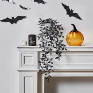 fledermäuse als wanddekoration und transparenter kürbis als atmosphärische halloween deko für kaminsims