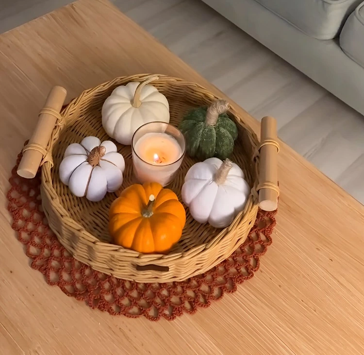Geflochtener Korb als Unterlage für eine Gruppe aus Deko-Kürbissen und für ein Windlicht
