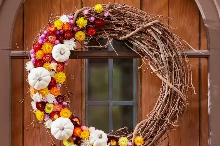 Herbstkranz mit frischen Blumen und weißen Zierkürbissen