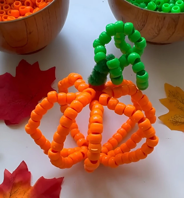 Kürbis basteln mit Pfeifenputzern und orangen und grünen Perlen