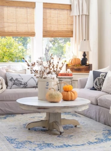 zu halloween passende und stilvolle herbstdeko 2023 mit dekorativen kissen und kürbissen auf dem couchtisch im wohnzimmer