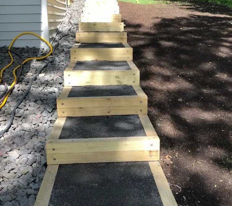 beim Anlegen eines Gartens am Hang mit Holzbrettern und Erde eine einfache Gartentreppe selber bauen