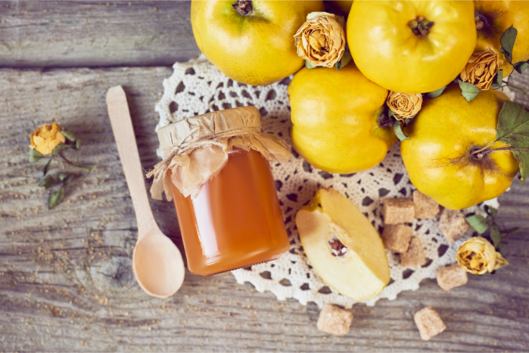 glas mit quittengelee auf rustikalem holzhintergrund