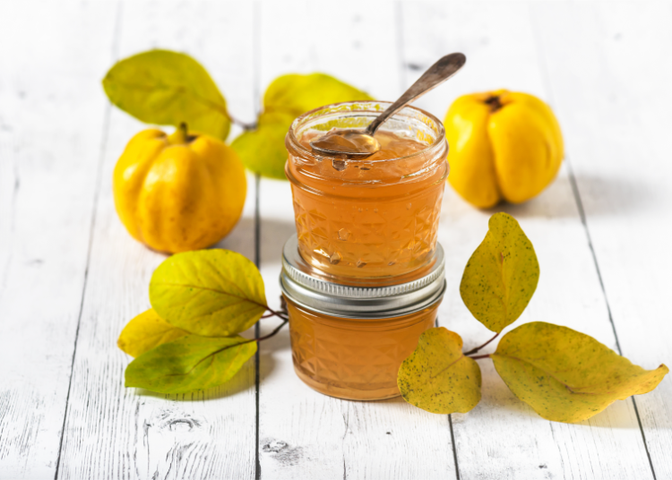 hausgemachte quittengelee in gläsern und frische quitten mit blättern