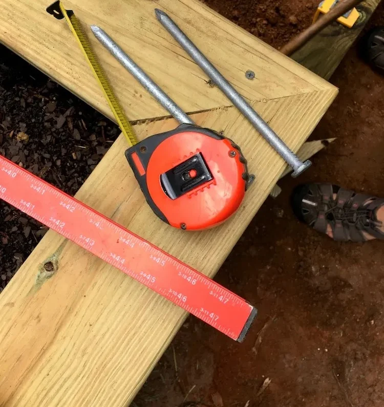 Instrumenten wie Maßband und Hammer mit Nägeln sowie Materialien wie Bewehrungseisen verwenden und Gartentreppe selber bauen
